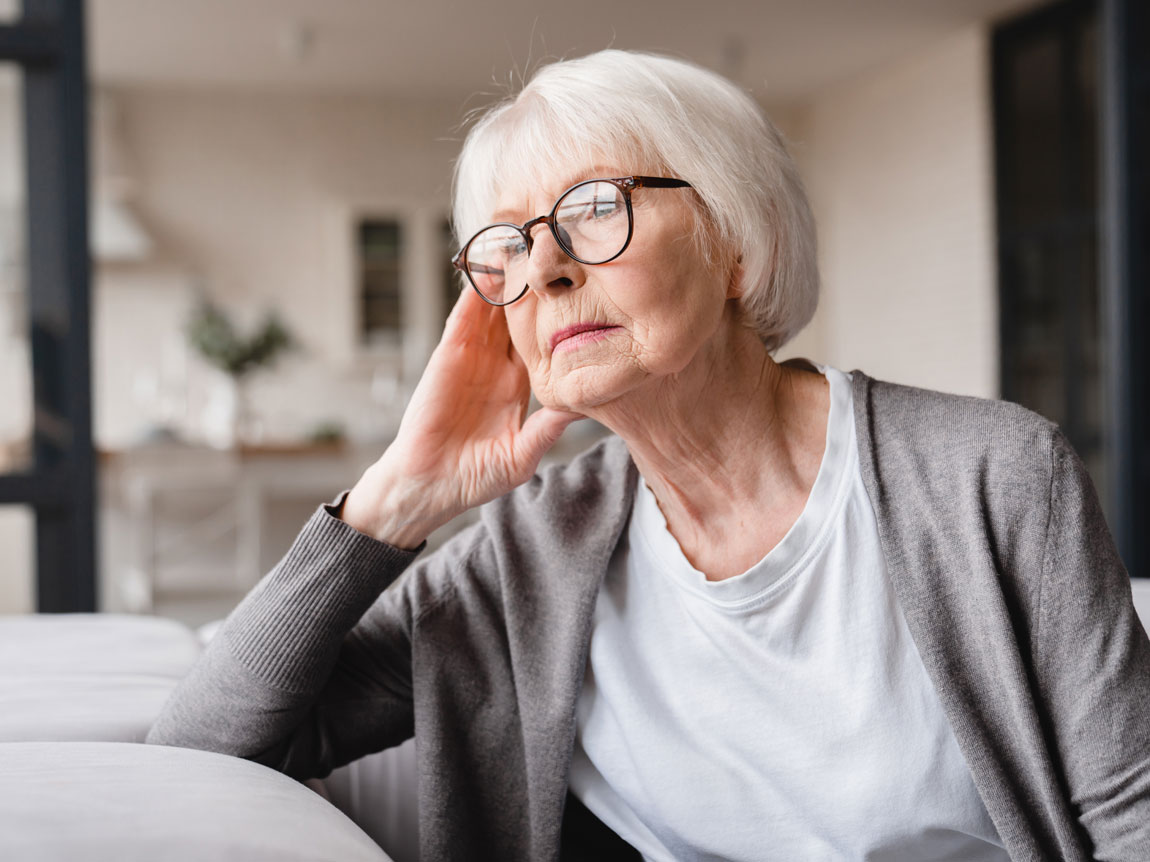 a senior woman with a lonely gaze towards a window.